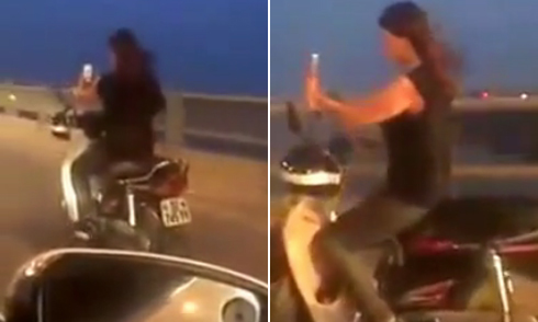 Cô gái một tay lái xe máy một tay chụp ảnh selfie